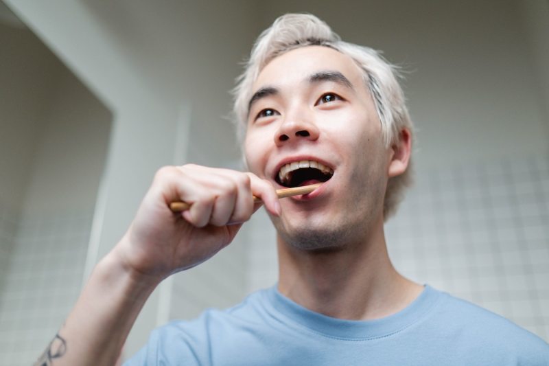 A man in a blue sweatshirt brushing his teeth